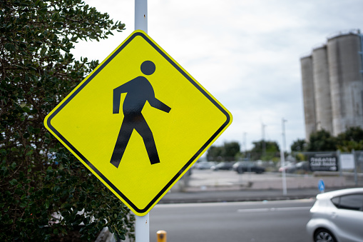 A yellow pedestrian access sign on a pole