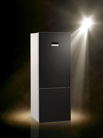 Spot lit stainless steel refrigerator on colored background
