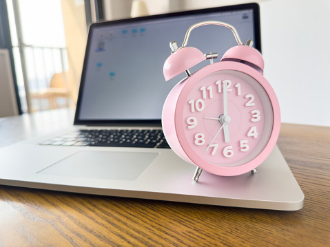 Laptop and retro alarm clock in a modern house on a desktop