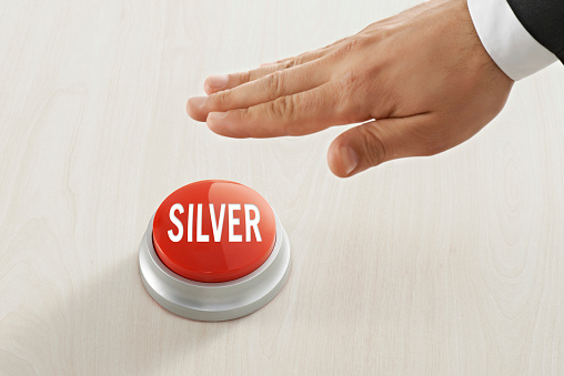 Businessman pushing “silver“ button on a table top symbolizing business investment