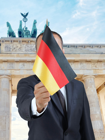 Businessman holding a German flag in front of Brandenburg gate