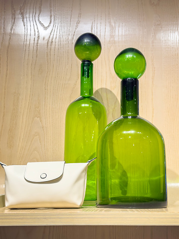 Still life of handmade glass carafes and leather bag on wooden background
