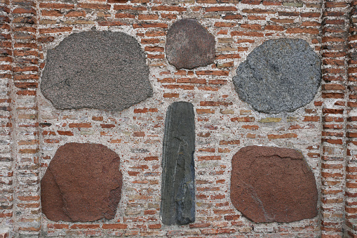 cracked brick wall of rectangular red clay bricks and large stones, cobblestones. The background.