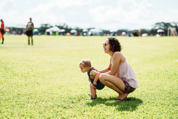 Mother holds son while watching an adult soccer game