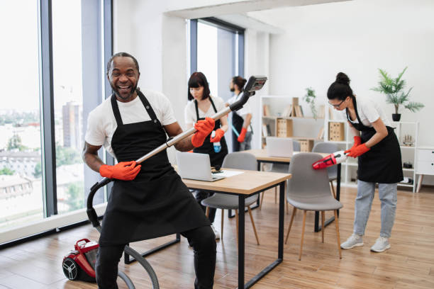 istock Happy multinational team of people in black aprons cleaning modern office. 1943841875