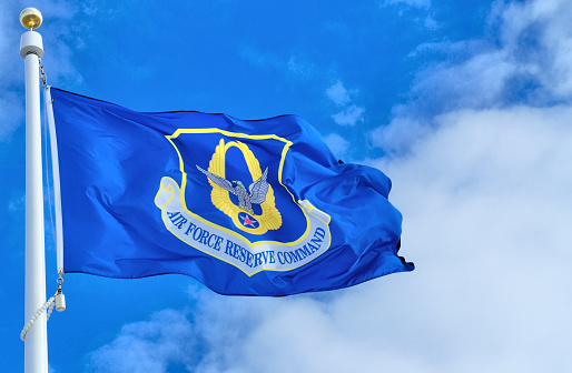 U.S. Air Force Reserve flag against a blue sky and white cloud background