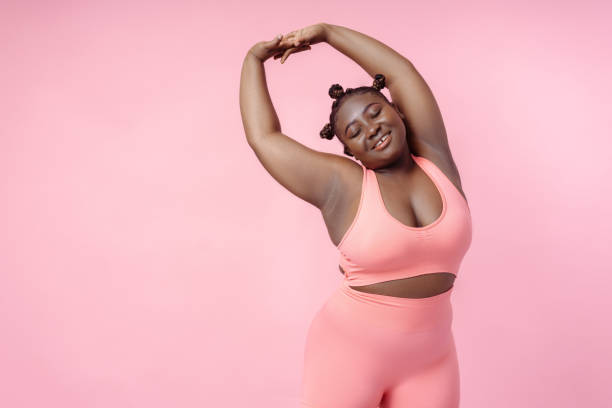 istock Smiling African American woman stretching, training, doing exercises isolated on pink background 1943858292