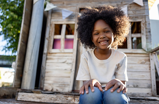 Happy African American girl playing in her tree house and looking at the camera smiling
