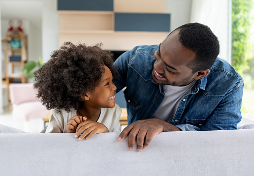 Loving African American father and daughter having fun at home and smiling - family concepts