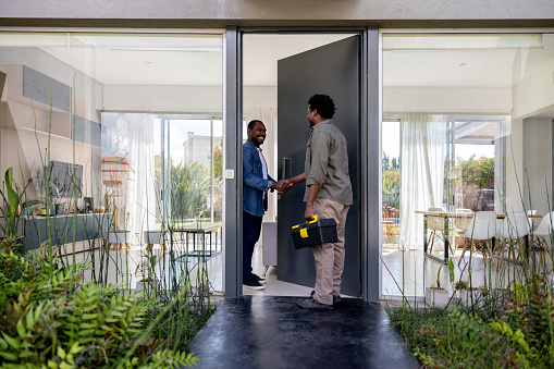 Electrician arriving to a house for a service and greeting the owner at the door with a handshake