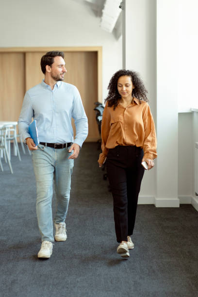 istock Handsome male bearded manager and his female assistant walking around modern office, talking 1943864186