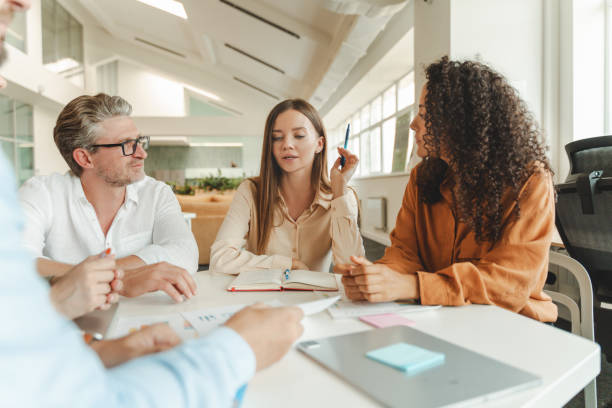 istock Confident businesswoman sitting at workplace working with colleagues, brainstorming, sharing ideas 1943864741