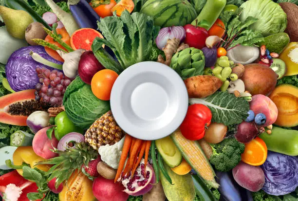Eating A Healthy Diet as a nutrition symbol of a plant based dietary choice with an empty plate to eat high nutrient foods as vegetables fruit legumes beans and nuts for wellness and health representing farm fresh raw ingredients and agriculture