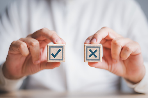 Businessman think and make choices between right and wrong symbols on wooden cubes. Decide to vote concept. Yes or No decisions, business options in difficult situations, crisis decision making.