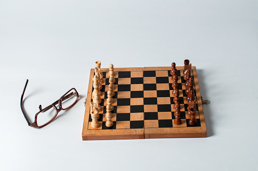 A beautiful handmade, hand-stained wooden checkerboard and checkers sits ready for a game. Nice woodgrain detail throughout. Sitting on an arborite countertop which has a slightly textured, rich green matte finish and is NOT completely smooth. Strong lighting highlights the board, and softens the surrounding area.
