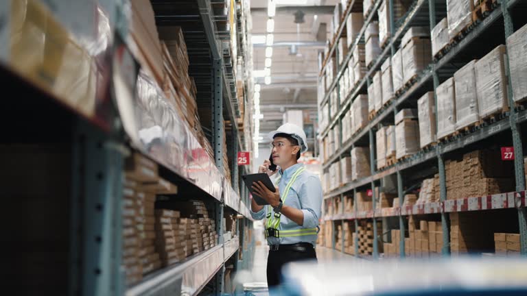Manager or supervisors use smartphone while to check the stock inventory on shelves in large warehouses, a Smart warehouse management system, supply chain and logistic network technology concept.