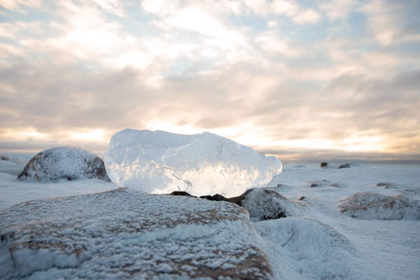 A snowy block of ice on the seashore under a colorful half-cloudy sky