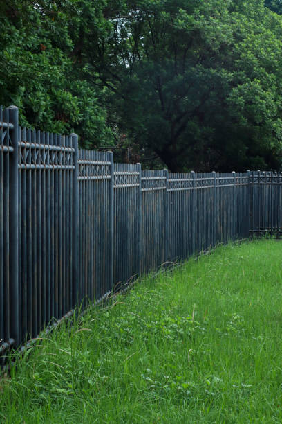 istock Worn iron fence, with green grass and trees 1944008964