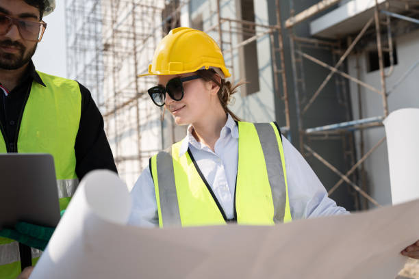 istock Caucasian engineer man and woman working with paper work at construction site 1944052626