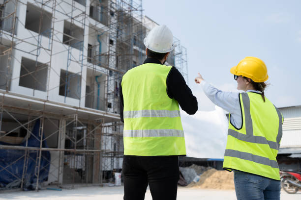 istock Caucasian engineer man and woman finger point to building with paper work at construction site 1944058366