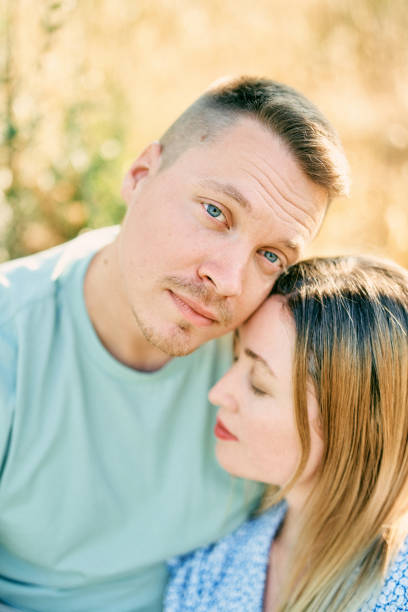 istock Guy touches girl head with his cheek while hugging her while sitting on the grass 1944065595