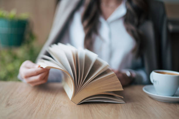 Black man hands paging a book in a cafe.