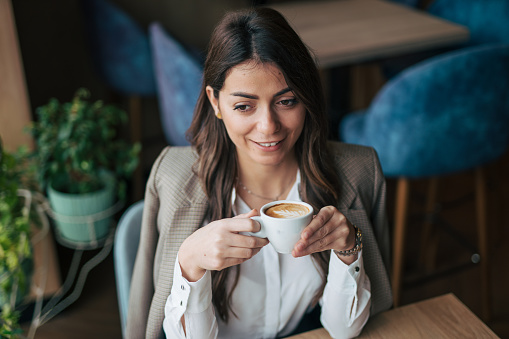 A woman enjoys a cappuccino in a cafe