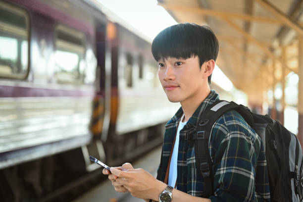 istock Attractive man using mobile phone during waiting for train at railway station 1944174883