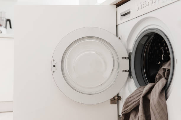 istock Opened Cabinet Door Revealing Integrated Washing Machine in White Kitchen 1944221124