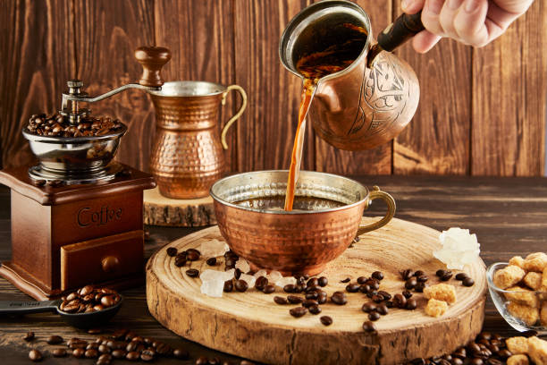 istock Pouring coffee from coffee maker into copper cup, an antique coffee grinder and copper milk jug on wooden background 1944223690