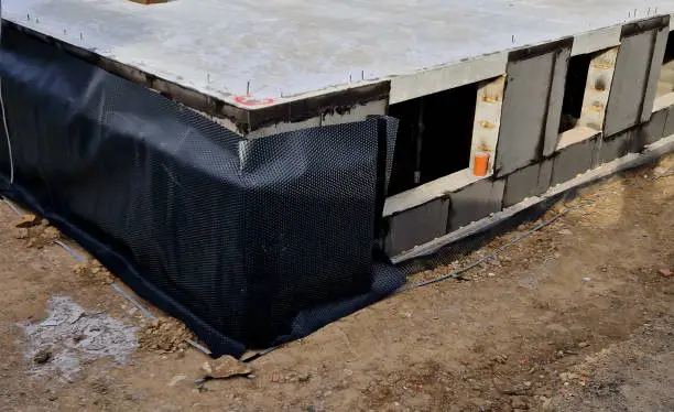 Photo of thermal insulation with polystyrene plates around the perimeter of the underground floor. insulation against water and moisture with fused foil. backfill around the building. sprinkle soil foundation