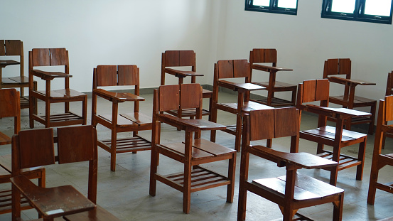 Old wooden chairs lined a simple, empty classroom.