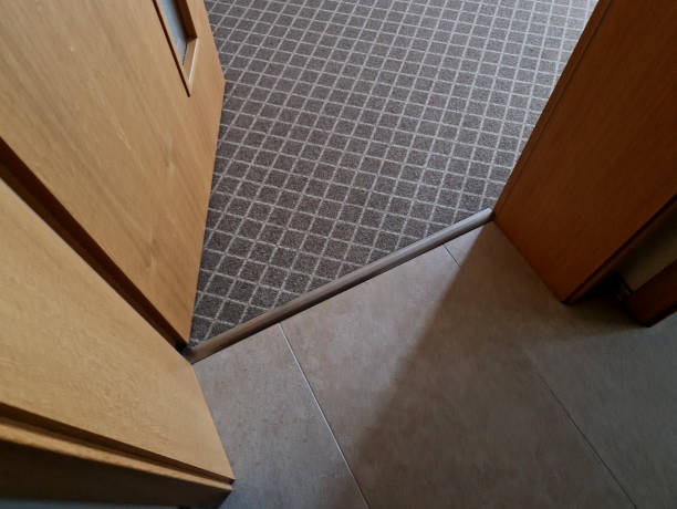 istock open door to a room with a grid pattern carpet in subtle colors with a short pile. transition strip made of aluminum between the paving and the carpet. door frames made of brown wood. 1944245418