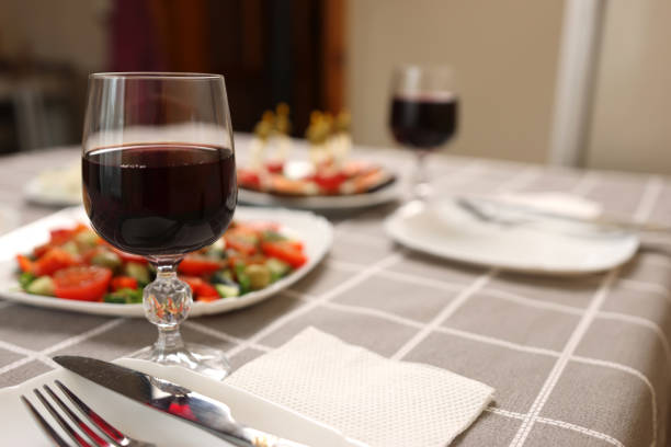 istock Red wine is poured into a glass on a table with festive dishes 1944255719