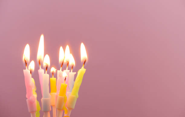 istock Birthday candles burning on pink background, copy space for text. 1944256248