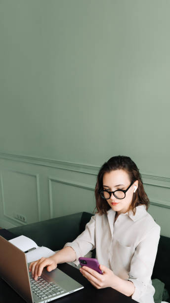 productive conversations. woman balancing laptop and smartphone in video call. multitasking joy. busy woman in glasses juggles video call on laptop and smartphone with a smile - variation meeting work tool isolated photos et images de collection