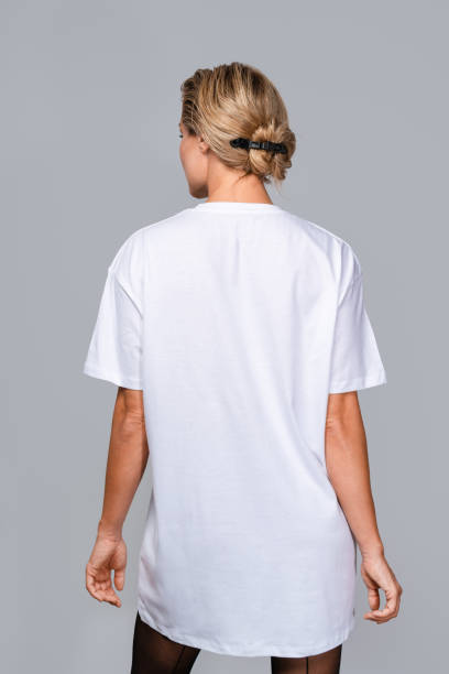 istock Woman dressed in a white oversized t-shirt with blank space, ideal for a mockup, set against gray background 1944263032