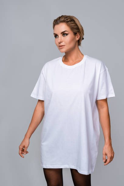istock Woman dressed in a white oversized t-shirt with blank space, ideal for a mockup, set against gray background 1944264061