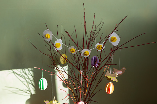 a vase filled with branches with paper craft fried eggs garland, folk art, Easter decoration hanging on tree, paper decoration, sunshine