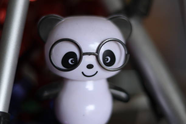 A Black and White cute solar powered panda wearing black glasses toy on a shelf, flashed