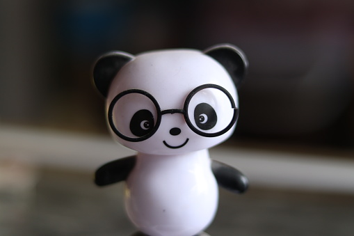 A Black and White cute solar powered panda wearing black glasses toy on a shelf, selective focus