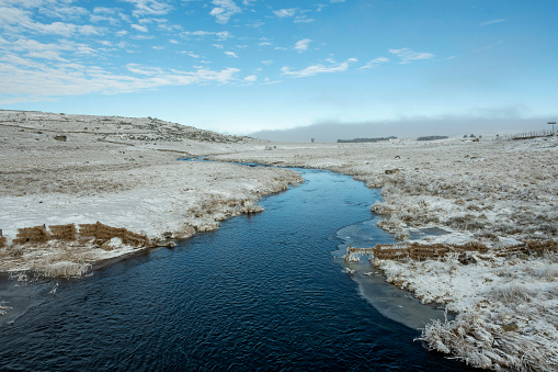 A scenic winter landscape with the Le Bes River. Aubrac, France
