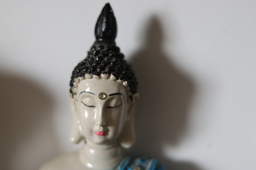 A religious ceramic statue of  Buddhism in a shelf on white wall