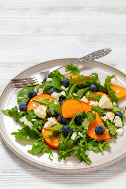 istock arugula persimmon cheese berries salad, top view 1944304846
