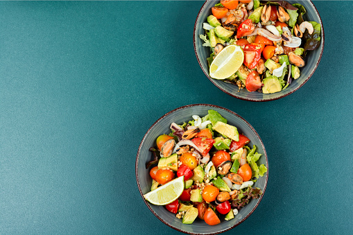 Delicious salad with fresh vegetables and seafood on a plate. Space for text.