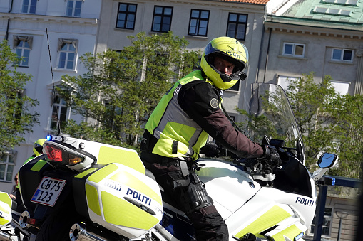 Danish policeofficer fully equipped on a policemotorbike in front of the danish Government Building of Christiansborg on a sunny day in Copenhagen, Denmark