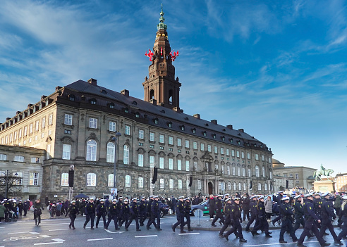 Danish police officers walking in a large group on their way to controlling the area around Christiansborg Palace, - the dansih government, building on a sunny winter day in Copenhagen, Denmark