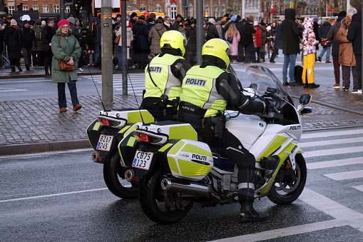 2 danish policeofficers fully equipped on policemotorbikes at a crossroad in front of the danish Government Building of Christiansborg on a sunny day in Copenhagen, Denmark