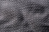 Dark gray textile background, structure of rough, pleated blanket close up