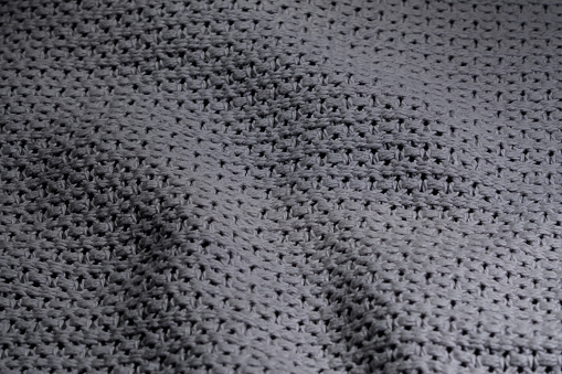 Background in grays, close-up of the structure of a folded gray knitted blanket isolated